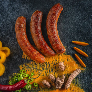 gebratene Bratwurst auf gelben Hintergrund umgeben von Chili Ingwer Gewürze