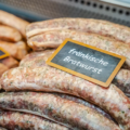 Rohe fränkische Bratwürste mit Schild in Metzgertheke