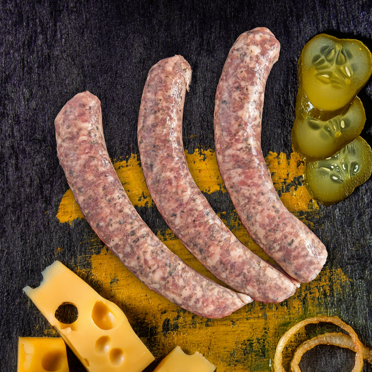 Drei rohe Bratwürste neben Emmentaler Käse Gewürzgurken Scheiben und Zwiebelringen.