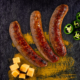 Drei gebratene Bratwürste neben Jalapeno Scheiben und Cheddar Würfeln.